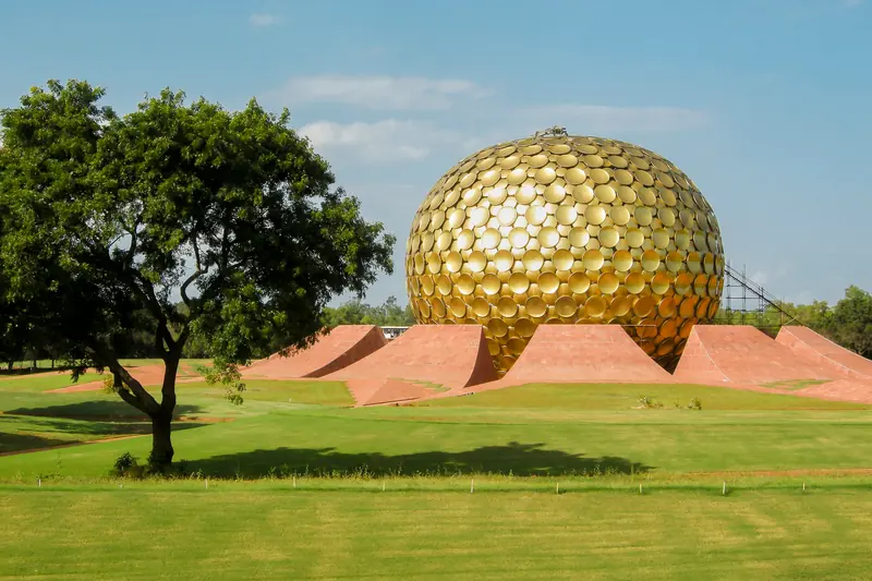 The golden Matrimandir dome on green lawns in Auroville