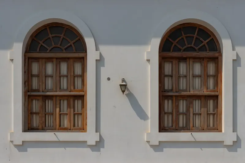 Arched wooden windows on a white French-colonial wall in Pondicherry