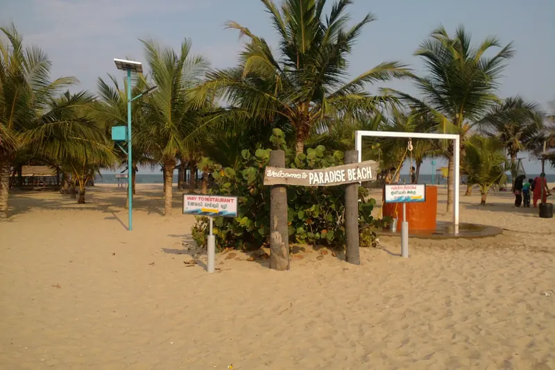 Palm trees and the Paradise Beach sign on the sand near Pondicherry
